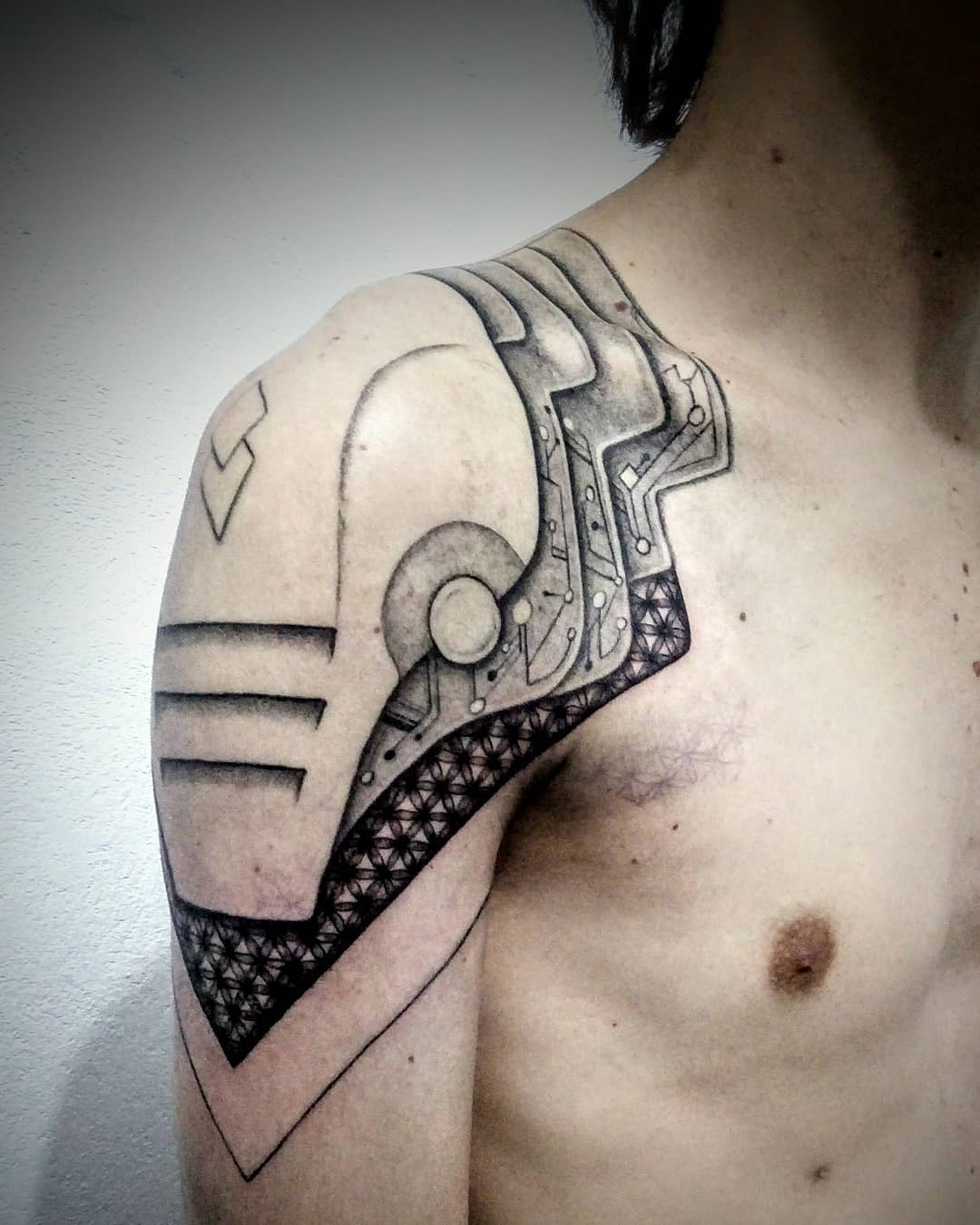 Cyberpunk tattoo on shoulder and upper arm, featuring mechanical and circuit-inspired elements with geometric patterns